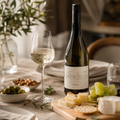 Weingut Sieferle Secco als eleganter Aperitif auf warm gedecktem Tisch mit Perlweinglas, Käse, Trauben, Oliven, Nüssen und natürlichen Materialien im Tageslicht.